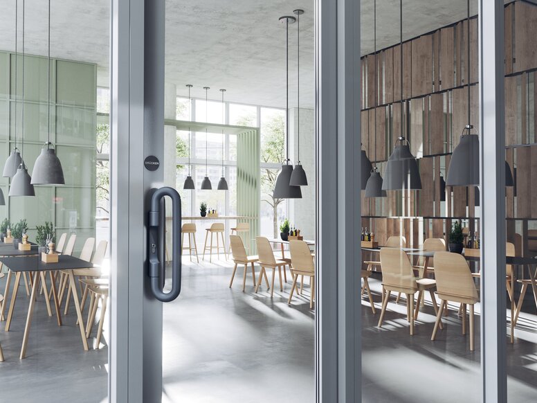 A dark grey door handle on a double glass door in a catering area