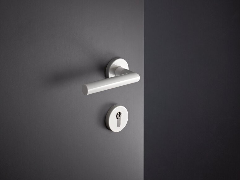 HEWI System 162 lever handle White synthetic material door handle with a round rosette and a lockable key cylinder, fitted to a grey door