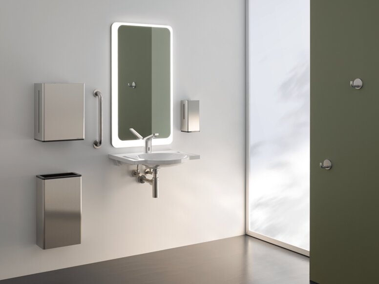 HEWI Serie 805 Interieur Beleuchteter Spiegel, darunter Handwaschbecken mit Papierspender und Abfalleimer an weißer Wand