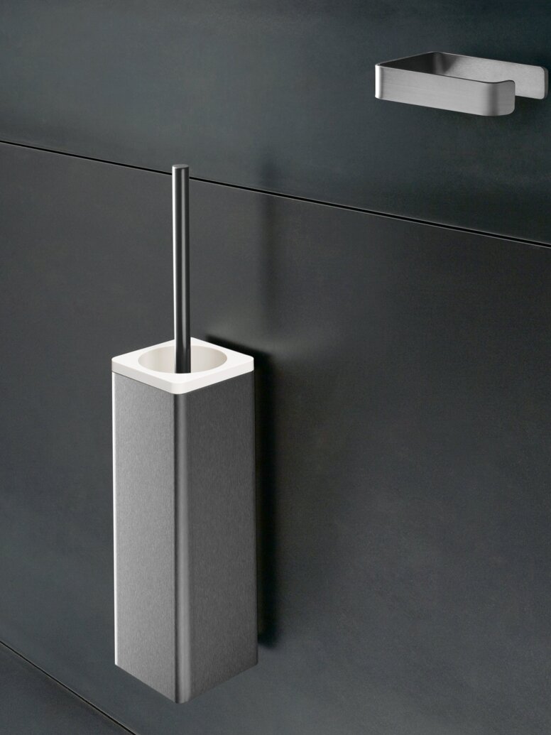 HEWI Range 805 toilet brush unit Stainless steel toilet brush unit with a rectangular container and brush handle on a dark grey wall, beneath a small wall bracket