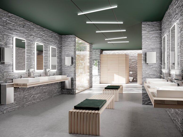 Several white washbasins with taps, mounted on two walls, each beneath illuminated mirrors in the public WC