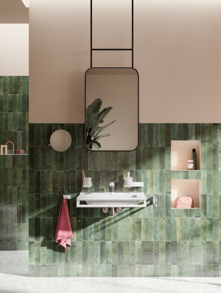 HEWI System 900Q Interior Accessible washbasin with tap, wall-hung WC and accessible shower area with a hinged seat against a green tiled wall