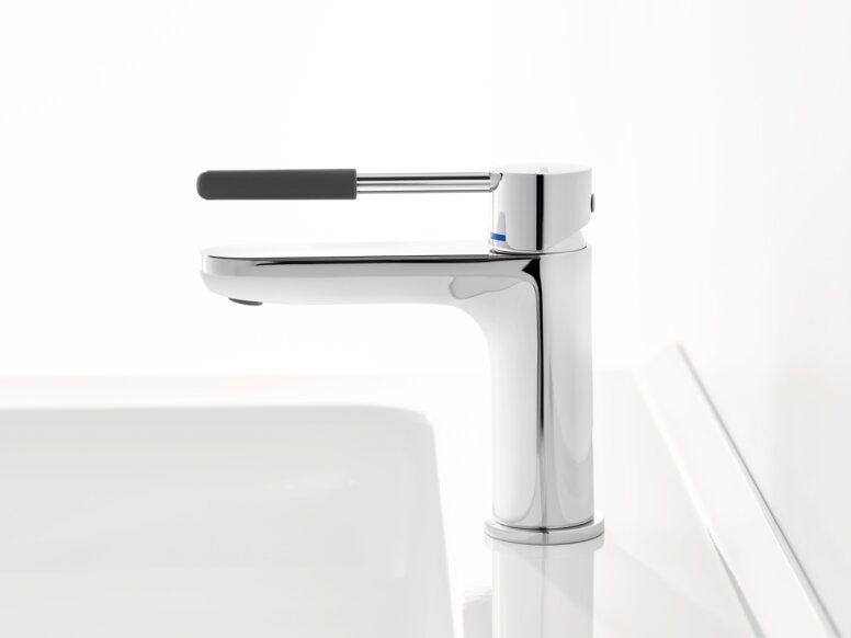 Chrome-plated tap with a long lever handle and dark grey grip sleeve on a white washbasin against a white background